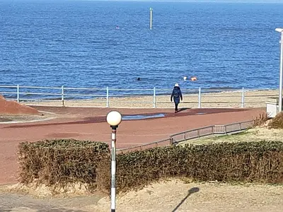 a person walking on a sidewalk next to the ocean at Morecambe Central balcony with sea view in Morecambe