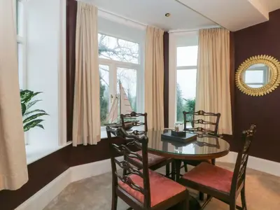 a dining room with a table and chairs and windows at Alexander in Preston