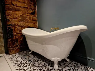 a white bath tub in a bathroom with a brick wall at The Duke in Preston