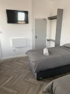 a bedroom with a bed and a television on the wall at The Glenbuck Hotel Anfield in Liverpool