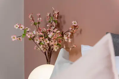 a vase with pink flowers in it next to some pillows at Riversleigh in Warton