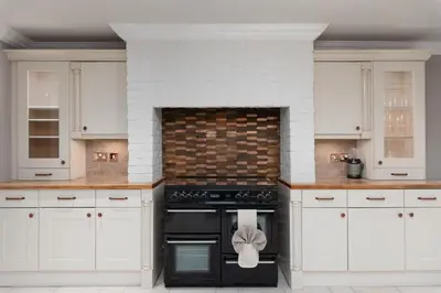 a kitchen with white cabinets and a black oven at Riversleigh in Warton