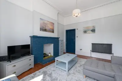 a living room with a couch and a fireplace at Bifolds, enclosed garden. Southport character home in Southport