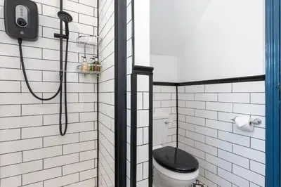 a bathroom with a shower with a black toilet at Bifolds, enclosed garden. Southport character home in Southport