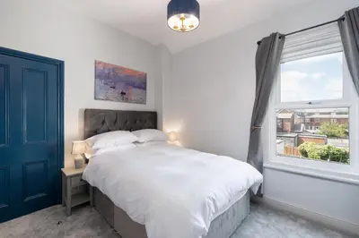 a bedroom with a large bed and a window at Bifolds, enclosed garden. Southport character home in Southport