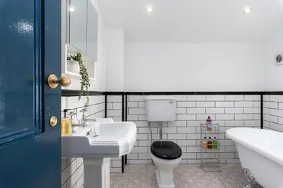 a bathroom with a sink and a toilet and a tub at Bifolds, enclosed garden. Southport character home in Southport