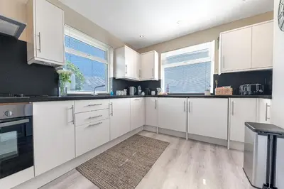 a white kitchen with white cabinets and windows at Colt Park Cottage in Ulverston