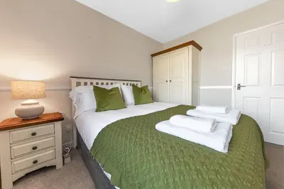 a bedroom with a green and white bed with towels on it at Colt Park Cottage in Ulverston