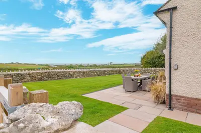 a patio with a table and chairs and a stone wall at Colt Park Cottage in Ulverston