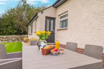 a table with a vase of flowers and fruit on it at Colt Park Cottage in Ulverston