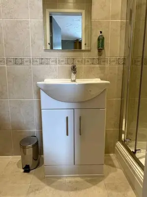 a bathroom with a white sink and a shower at O’er The Yard Hideaway in Blackpool