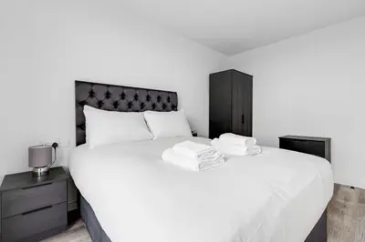 a bedroom with a large white bed with a black headboard at GuestReady - Delightful getaway in Liverpool in Liverpool