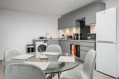 a kitchen with a glass table and chairs and a refrigerator at GuestReady - Delightful getaway in Liverpool in Liverpool