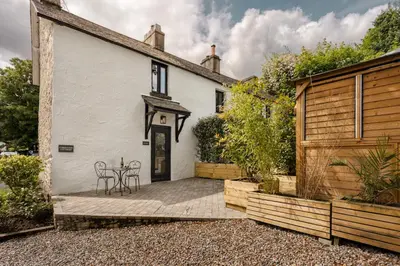 a white house with a table and chairs on a patio at Coronation Cottages, Modernised 200-Year-Old Lake District Cottage Getaway for Two - Ridgestone in Lindale