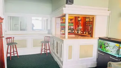 a bar in a room with two stools and a tv at Delamere Hotel in Blackpool