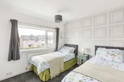 two beds in a room with a window at 3 Bed House - Sleeps 5 - Parking - Garden - Wifi in Blackburn