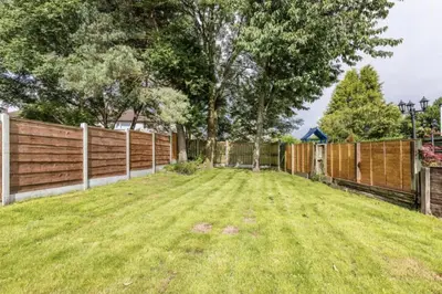 a backyard with a fence and a grass yard at 3 Bed House - Sleeps 5 - Parking - Garden - Wifi in Blackburn