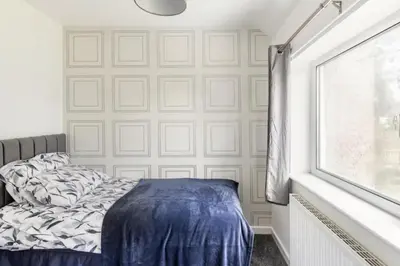 a bedroom with a bed and a white wall at 3 Bed House - Sleeps 5 - Parking - Garden - Wifi in Blackburn