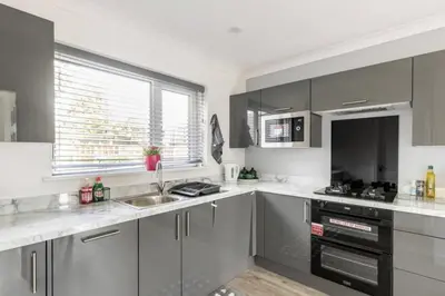 a kitchen with gray cabinets and a sink and a window at 3 Bed House - Sleeps 5 - Parking - Garden - Wifi in Blackburn
