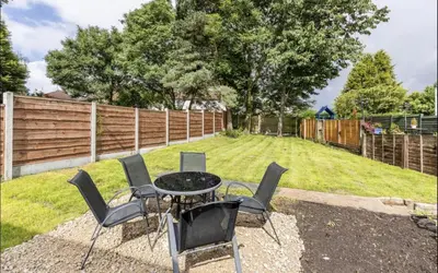 a table and chairs in a backyard with a fence at 3 Bed House - Sleeps 5 - Parking - Garden - Wifi in Blackburn