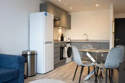 a kitchen with a table and chairs and a refrigerator at GuestReady - Lux getaway in Liverpool in Liverpool