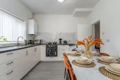 a kitchen with white cabinets and a table with chairs at Modern 4bedroom Spacious Family Home in Liverpool