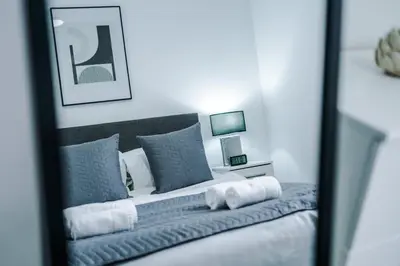 a bedroom with a bed with blue pillows and a mirror at Victoria Mill by Staycay in Wigan