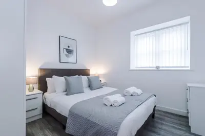 a white bedroom with two beds and a window at Victoria Mill by Staycay in Wigan