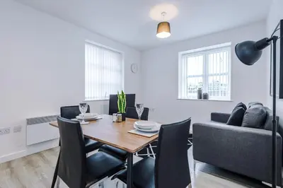 a dining room and living room with a table and chairs at Victoria Mill by Staycay in Wigan