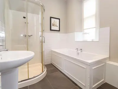 a white bathroom with a shower and a sink at Church View in Grange Over Sands