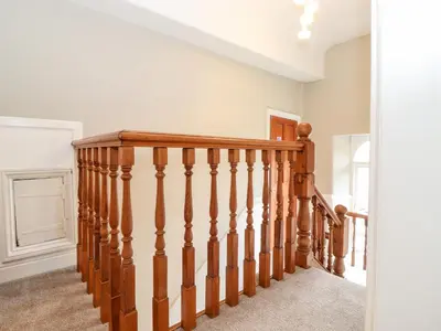 a wooden staircase in a home with white walls at Church View in Grange Over Sands