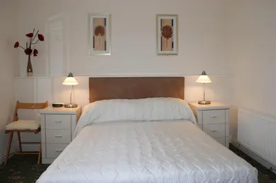 a bedroom with a bed with two night stands and two lamps at Beachcomber Hotel in Blackpool
