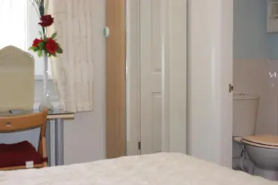 a bathroom with a toilet and a vase with a flower at Beachcomber Hotel in Blackpool