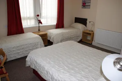 a hotel room with two beds and two windows at Beachcomber Hotel in Blackpool
