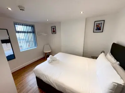 a bedroom with a white bed with a stuffed animal on it at Beach House By Sasco in Blackpool