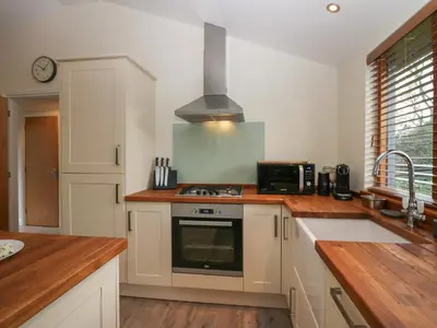 a kitchen with white cabinets and a stove top oven at Bay Tree Lodge in Grange Over Sands