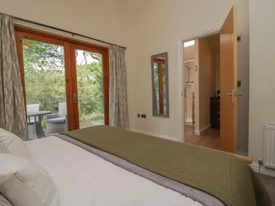 a bedroom with a large bed and sliding glass doors at Bay Tree Lodge in Grange Over Sands