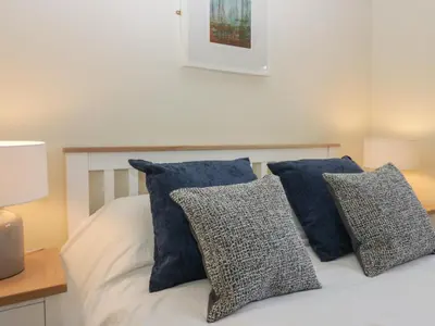 a white bed with blue pillows on it at Bay Tree Lodge in Grange Over Sands