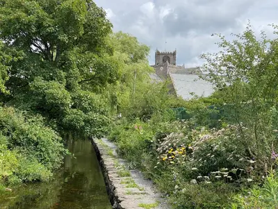 a garden with a river with a church in the background at Bay Tree Lodge in Grange Over Sands