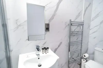 a white bathroom with a sink and a mirror at Spacious 3 Bed Apartment in Waterloo Liverpool in Waterloo