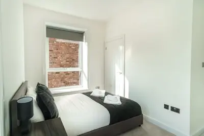 a white bedroom with a bed and a window at Spacious 3 Bed Apartment in Waterloo Liverpool in Waterloo