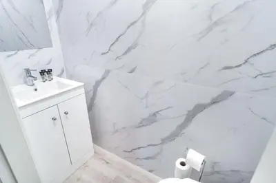 a white bathroom with a sink and a marble wall at Spacious 3 Bed Apartment in Waterloo Liverpool in Waterloo