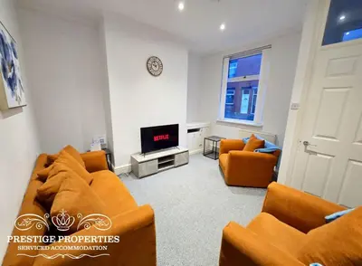 a living room with two orange couches and a tv at 31 Westmorland Street by Prestige Properties SA in Barrow in Furness