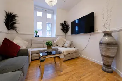 a living room with a couch and a tv on a wall at Sidemersey Livings - Spacious Loft for bigger groups - Very Central and Cosy in Liverpool