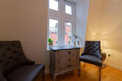 a living room with a chair and a dresser and a window at Sidemersey Livings - Spacious Loft for bigger groups - Very Central and Cosy in Liverpool