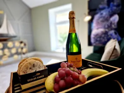 a bottle of champagne and a tray of grapes and bread at Hamilton-The Cruck Luxury Let in Scorton