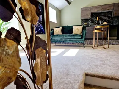 a living room with a green couch and a fireplace at Hamilton-The Cruck Luxury Let in Scorton