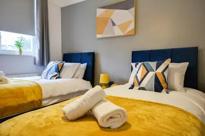 a bedroom with two beds with yellow and blue at Beautiful Stylish 2BD Flat - Free Parking 30 Percent Off Long term bookings in Wallasey