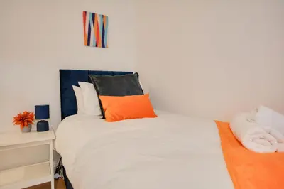 a bedroom with a white bed with orange pillows at Beautiful Stylish 2BD Flat - Free Parking 30 Percent Off Long term bookings in Wallasey