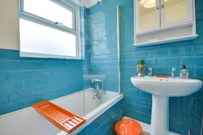 a blue tiled bathroom with a sink and a bath tub at Beautiful Stylish 2BD Flat - Free Parking 30 Percent Off Long term bookings in Wallasey